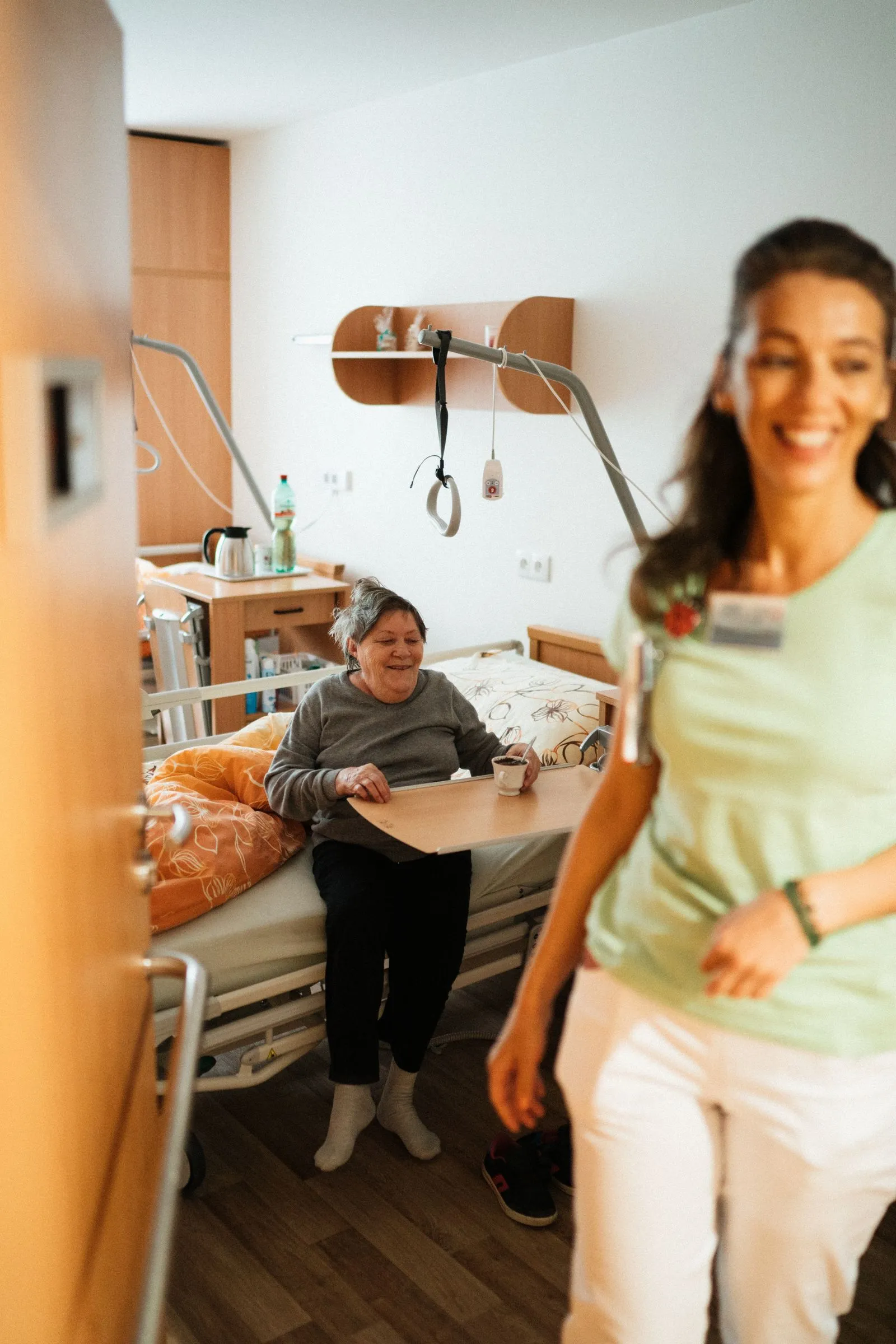 Zorgmedewerker loopt lachend door de gang van een zorginstelling