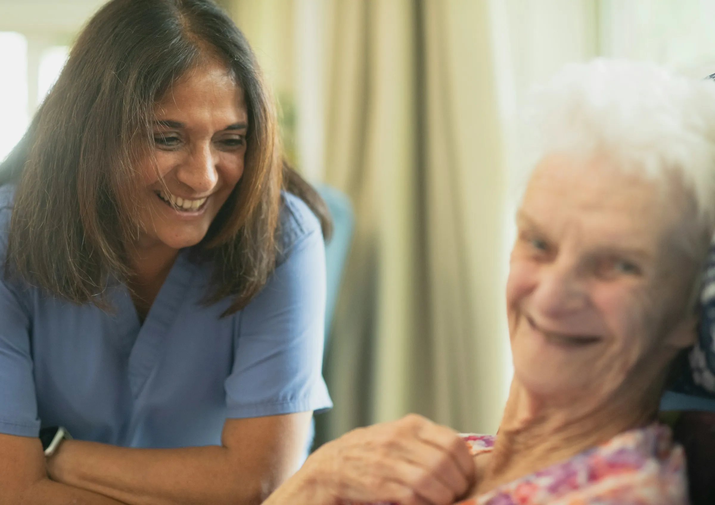 Zorgmedewerker en oudere bewoner lachen samen