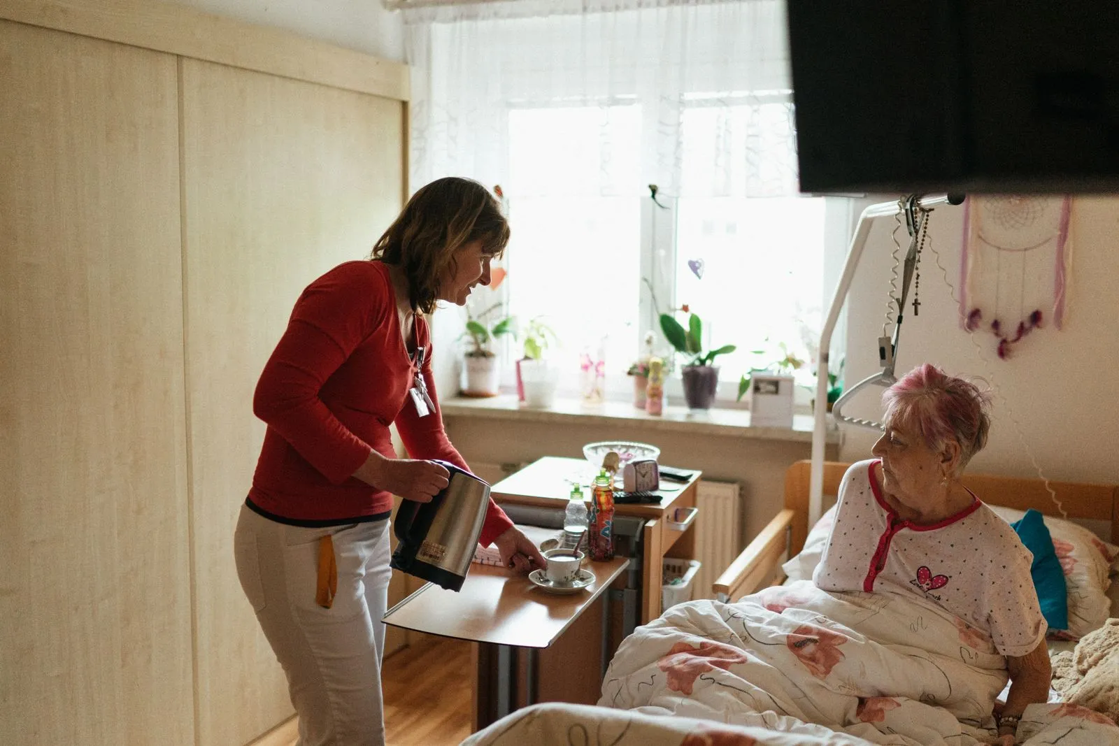 Zorgmedewerker schenkt thee in voor een oudere bewoner in haar kamer